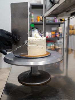 Decorator using spatula and scraper to smooth buttercream on a frosted cake