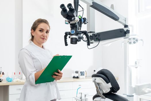 Smiling female dentist holding a clipboard with patient records in hands at dental clinic