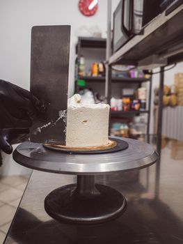 Decorator using spatula and scraper to smooth buttercream on a frosted cake