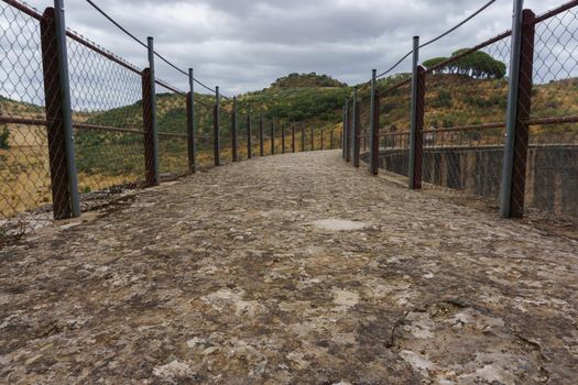 footbridge at the top of a dam over a swamp cloudy storm sky