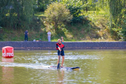 A man swims on a surfboard, pushing off with an oar. Paddleboarding. Russia Zelenograd 14 August 2021