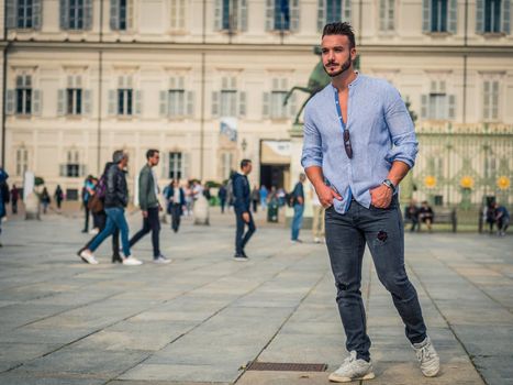 Young attractive man in European city street walking around, looking around