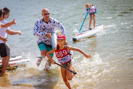 The girl runs from the board to the shore, hurries to the finish line. Paddleboarding. Russia Zelenograd 14 August 2021