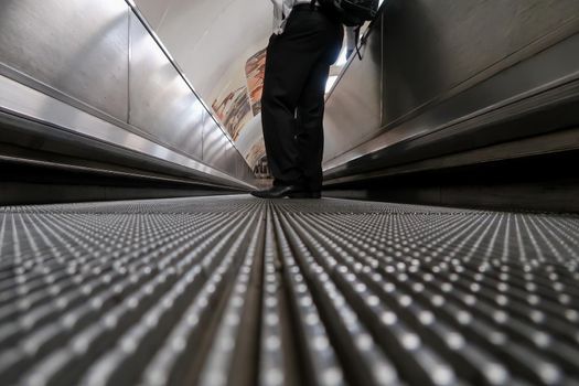 Low angle view of a male commuter standing on moving walkway