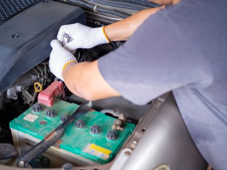 Mechanic holding a block wrench handle while fixing a car.