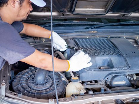 Mechanic holding a block wrench handle while fixing a car.