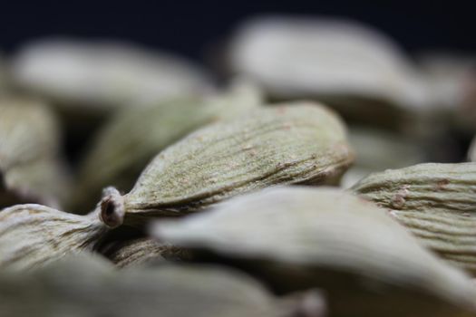 Closeup top view of dried green Elettaria cardamomum fruits with seeds, cardamom spice scattered on white background