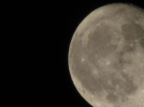 Earth's Moon Glowing On Black Background. The Moon close-up on a black night sky shot through a telephoto camera.