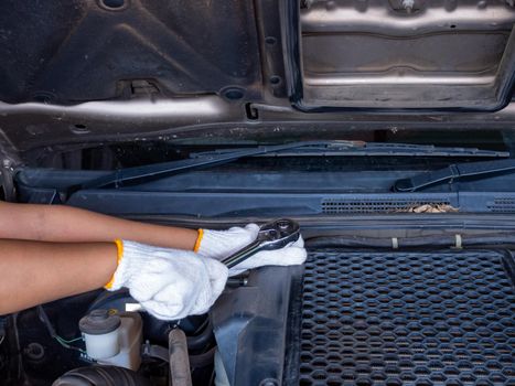 Mechanic holding a block wrench handle while fixing a car.