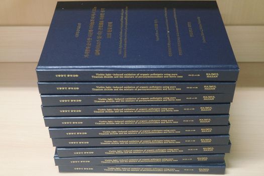 Stack of blue books placed on table. Thesis books with golden words on blue hardcover