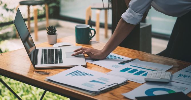 Business woman working with laptop computer and calculator to financial documents report on her desk. Business Accounting Concept.