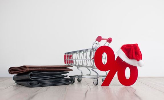 Shopping cart from the supermarket and sign percent with Santa hat on white background. Shopping in the Mall, shop, shopping, a large selection.
