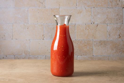 A glass jar bottle with homemade tomato sauce stands on the table. Selective focus.