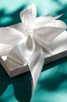 Anniversary celebration, shop sale promotion and bridal surprise concept - Luxury holiday white gift box with silk ribbon and bow on emerald green background, luxe wedding or birthday present