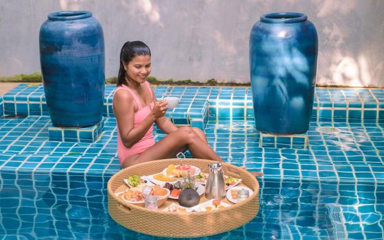 A women having breakfast in the swimming pool, Asian women having floating breakfast in the pool
