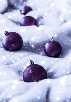 Gift decor, New Years Eve and happy celebration concept - Violet Christmas baubles on fluffy fur with snow glitter, luxury winter holiday design background