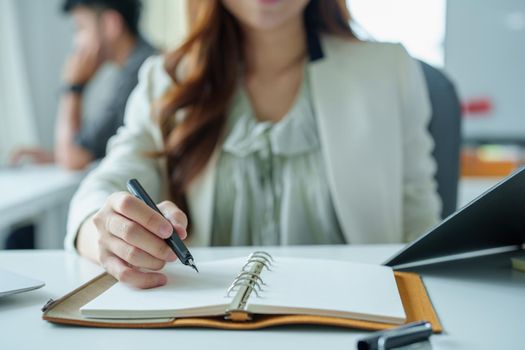 Portrait of an Asian bank employee using notebooks to take notes, budget documents and computers to close financial statements.