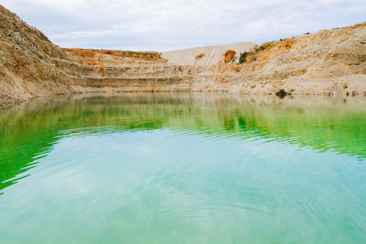 Lake formation in an old abandoned quarry. Quarry lake. Crushed stone dumps in a closed area for stone extraction. Termination of mining operations.