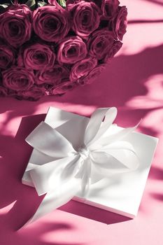 Happy holidays, luxe shopping and love gifts concept - Luxury holiday silk gift box and bouquet of roses on pink background, romantic surprise and flowers as birthday or Valentines Day present