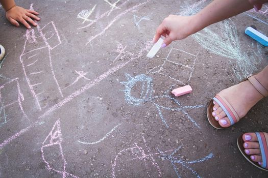 Children draw with chalk on the road. Children's creativity on the street. Entertainment in nature.