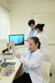 Professional scientists wearing white coats conducting experiment in research laboratory. Scientific research and technology concept.