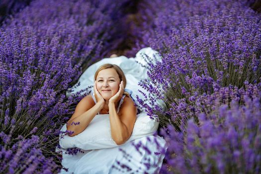 A middle-aged woman lies in a lavender field and enjoys aromatherapy. Aromatherapy concept, lavender oil, photo session in lavender.