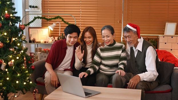 Image of happy family celebrating Christmas together at home lighted with soft lights and candles. Celebration, holidays and people concept.