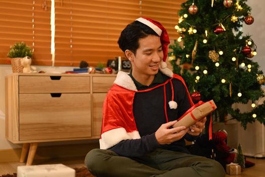 Happy emotional man with Christmas gifts and sitting in decorated room for celebrating New year and Christmas festive.