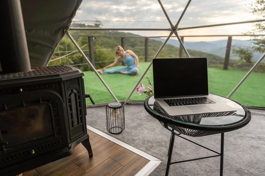 a woman does yoga on the terrace in a geo dome glamping tent.
