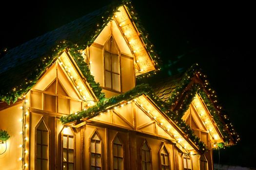 giving out or reflecting a lot of light, shining. Night glowing yellow golden house with lights and illuminations.