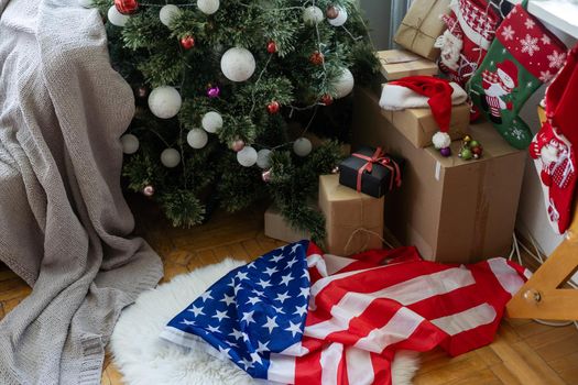 Close-up of gift boxes and a Christmas tree with an American flag in the background. Space for text. Concept of Christmas and new year festival