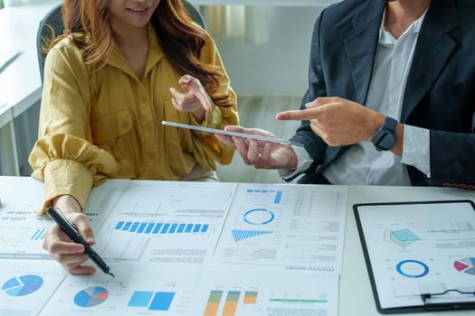 A portrait of a female business owner consulting a male salesperson to devise a strategy to increase revenue from new incoming goods using investment budget documents and an analytical computer.
