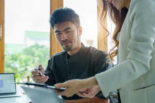 A portrait of a female marketer and a male salesperson discussing how to increase sales by investing in new products to expand marketing using documents and computers in working, new idea product.