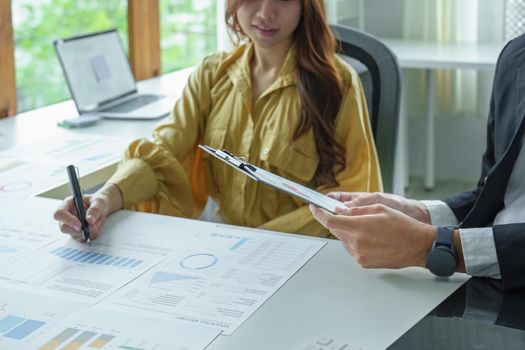 A portrait of a female business owner consulting a male salesperson to devise a strategy to increase revenue from new incoming goods using investment budget documents and an analytical computer.