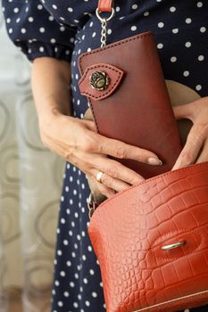 Woman takes a brown natural leather wallet out of her purse. Wallet made of genuine leather, a beautiful and practical women's accessory.