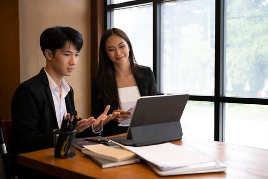 Two businesspeople discussing information on digital tablet together.