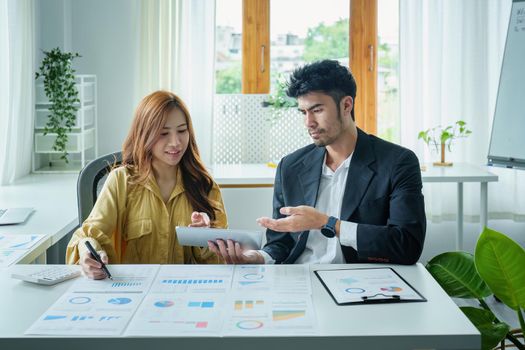 A portrait of a female business owner consulting a male salesperson to devise a strategy to increase revenue from new incoming goods using investment budget documents and an analytical computer.