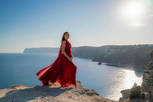 A woman in a red flying dress fluttering in the wind, against the backdrop of the sea