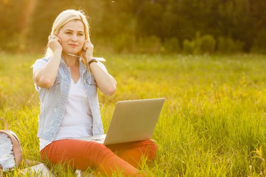 Euphoric woman searching job with a laptop in an urban park in summer