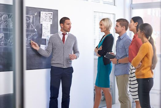 Communication is the brother of leadership. A businessman standing and presenting a storyboard to his team in an office