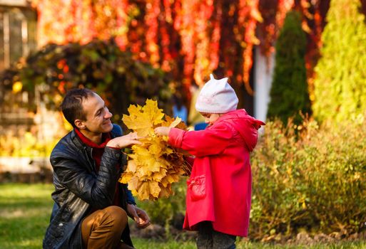 Happy family. daughter kissing and hugging her dad on a walk in the autumn leaf fall in park