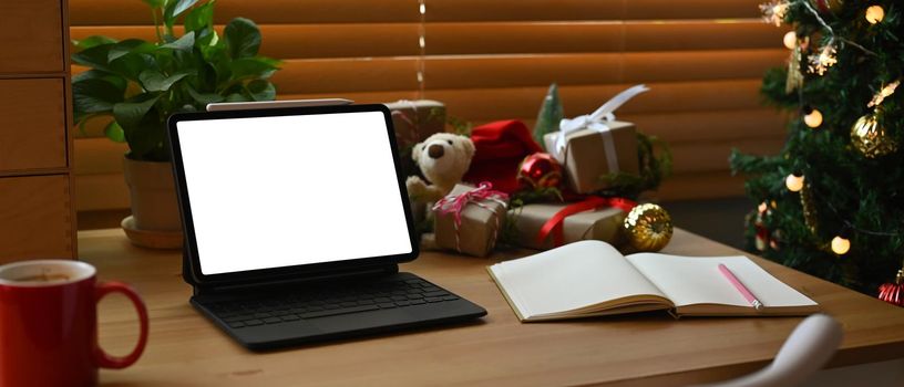 Mock up computer notebook, coffee cup and Christmas gifts on wooden table.