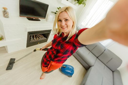 Woman cleaning floor vacuum cleaner in the modern white living room.
