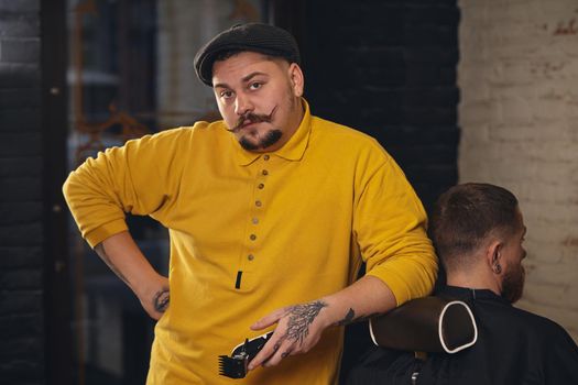 Barber making haircut and posing for the camera leaning on the client