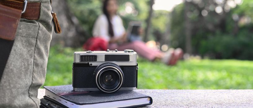 Camera, coffee cup and backpack on bench in the park.