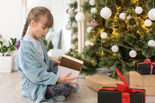 little child girl is decorating the Christmas tree indoors. The morning before Xmas.