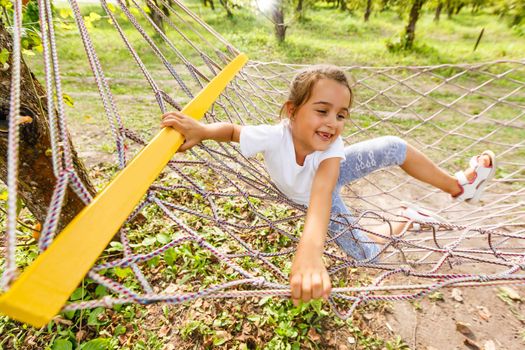 Happy Child Lying in Hammock. Cute Smiling Little Girl rides in Hammock in Nature. Pleasant summer leisure.