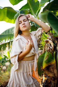 Woman near large green leaf of banana tree on nature in park. Tropical plants