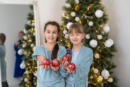 Two cute little girls under Christmas tree. Children under Christmas tree with gift boxes. New Year's decorations. Sisters.