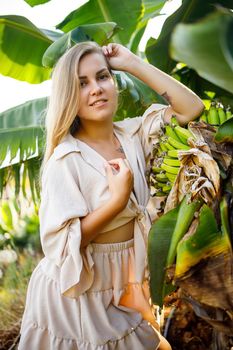 Woman near large green leaf of banana tree on nature in park. Tropical plants